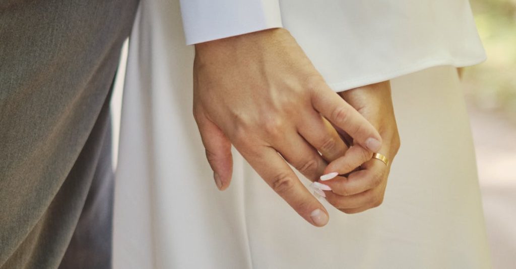 Close-up of a couple's hands intertwined, symbolizing love and unity on their wedding day. what is love